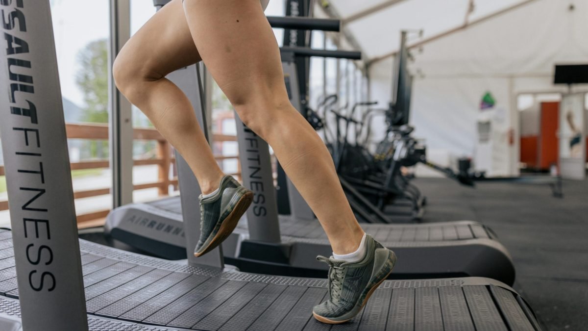Close-up of a woman's legs running on a treadmill indoors, focusing on fitness and exercise.