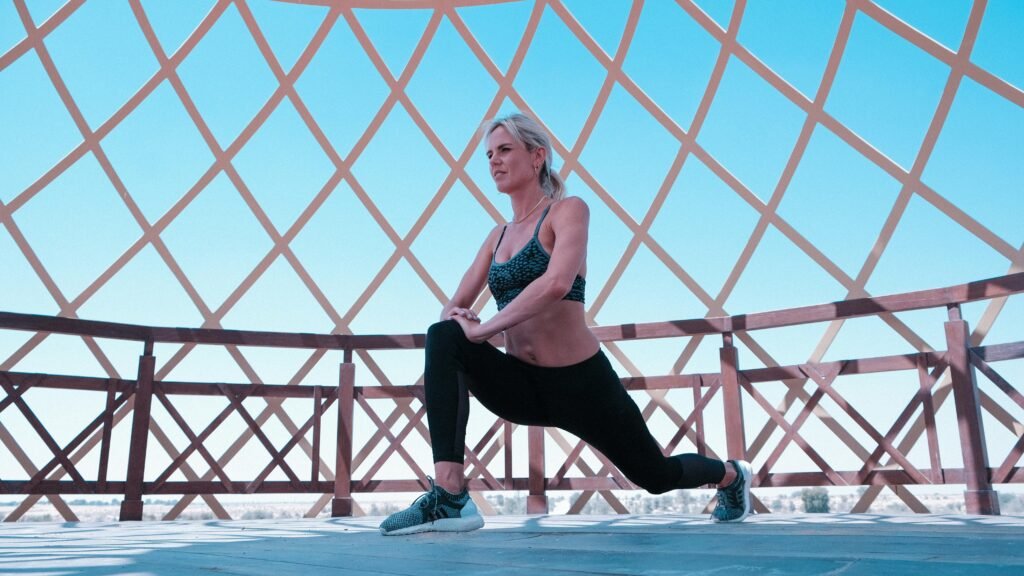 Woman performing leg lunges under a modern geometric canopy outdoors.