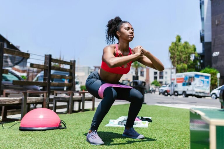 African American woman exercising with a resistance band outdoors.