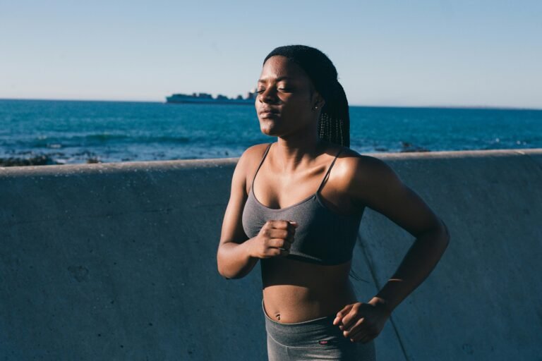 A young woman in activewear jogging along the ocean, embracing a healthy lifestyle.